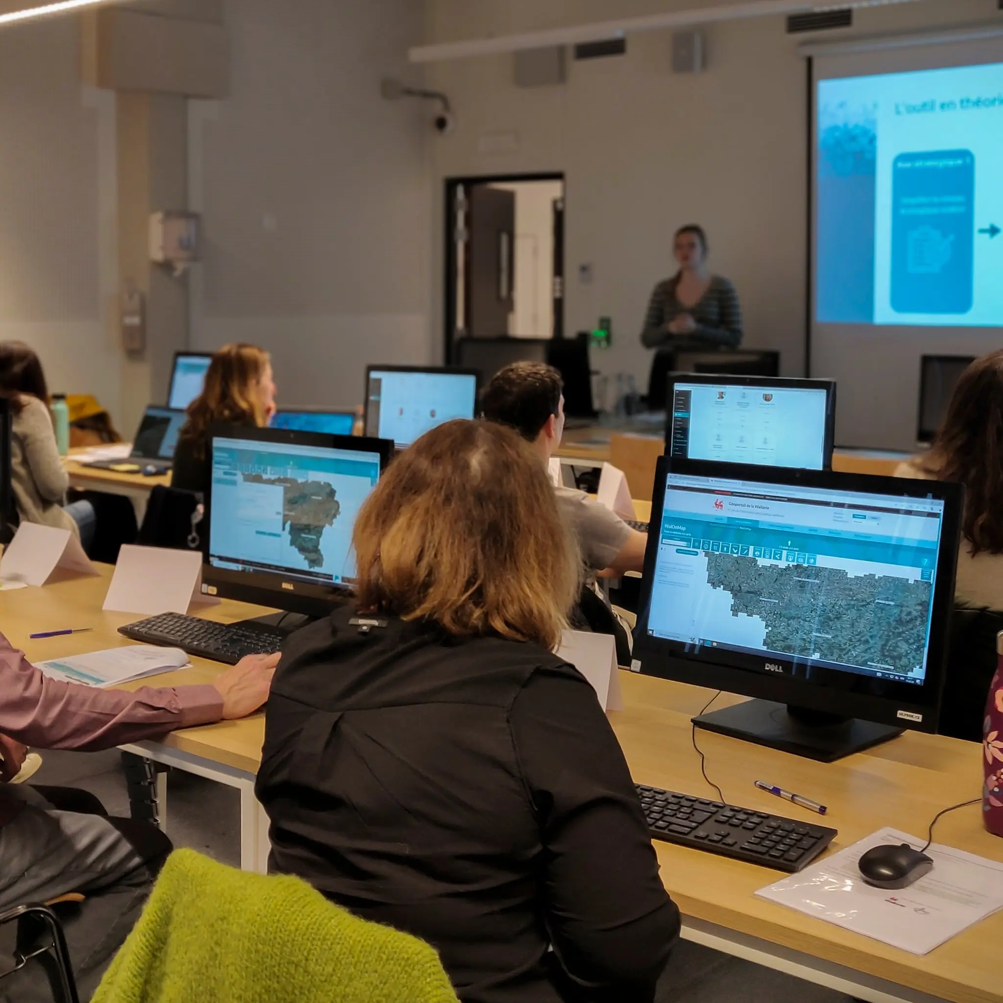 Des personnes assises devant des écrans d'ordinateurs et suivant une formation sur la plateforme Walonmap