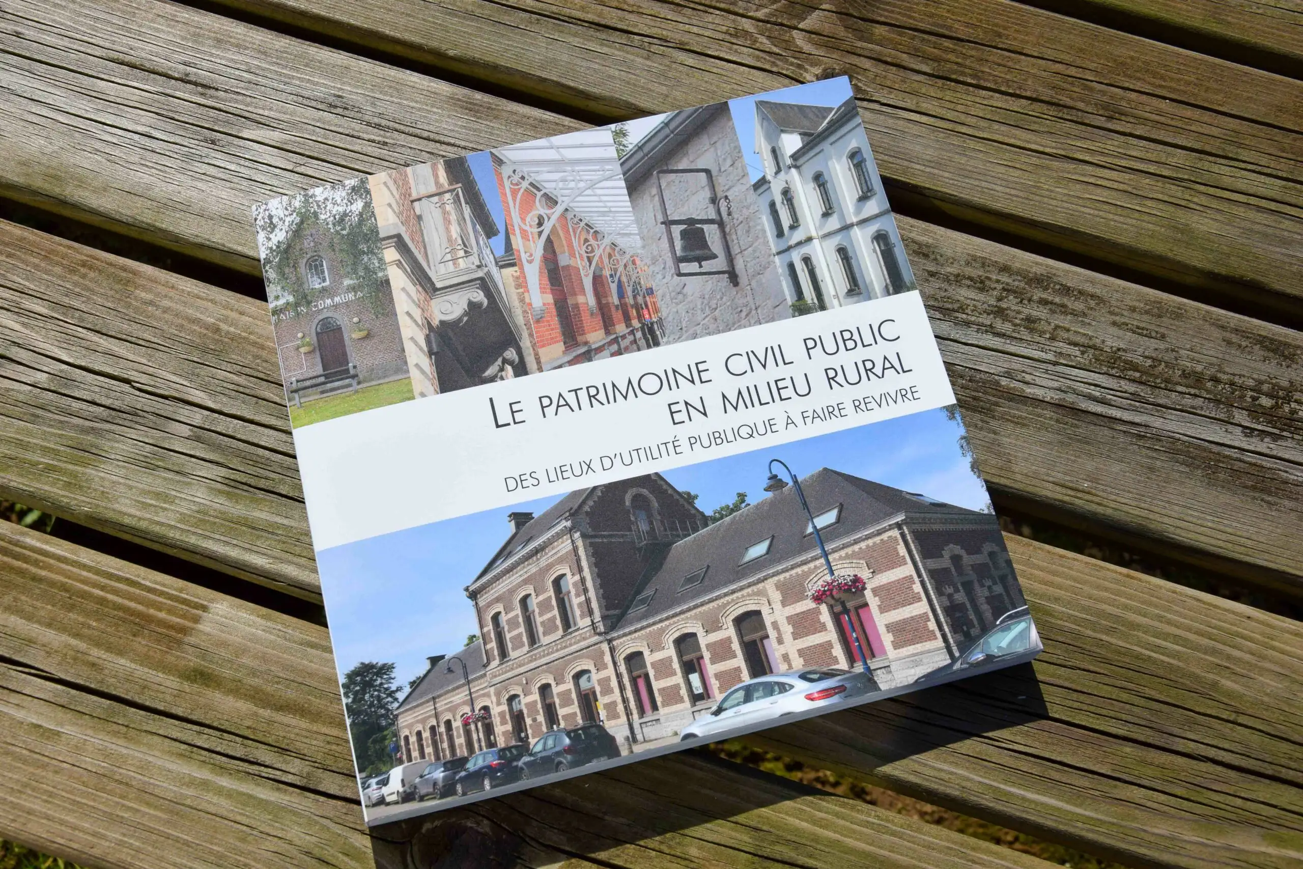 Exemplaire de l'ouvrage 'Le patrimoine civil public en milieu rural : des lieux d'utilité publique à faire revivre', déposé sur un banc en bois avec la couverture vers le haut.
