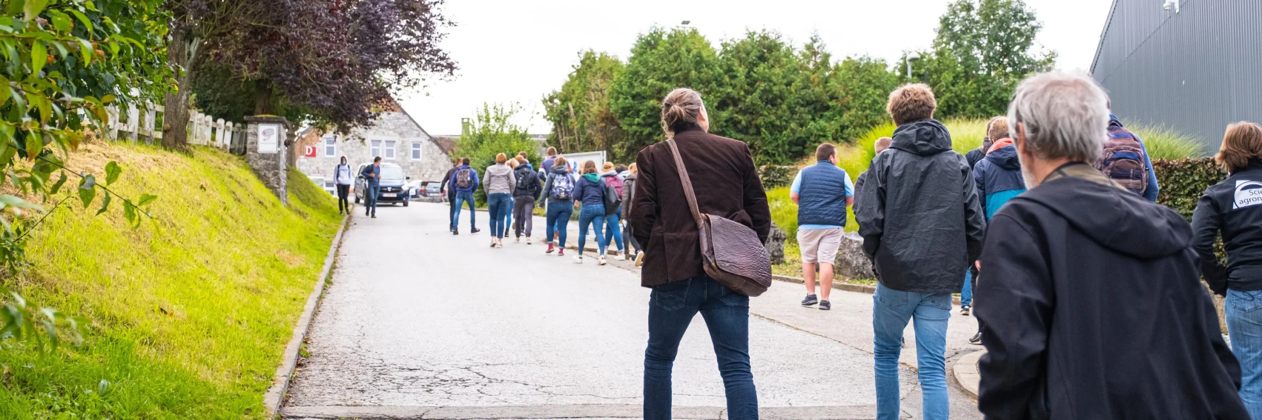 Une vingtaine de personnes, jeunes et moins jeunes, qui remontent une rue villageoise.