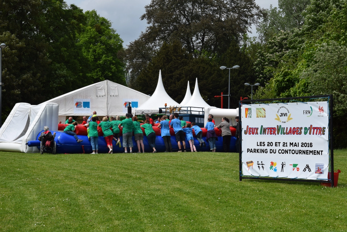 Événement extérieur avec structures gonflables : Un groupe de personnes participant à un événement en plein air avec des structures gonflables. Il y a une grande tente blanche et plusieurs petites tentes en arrière-plan.