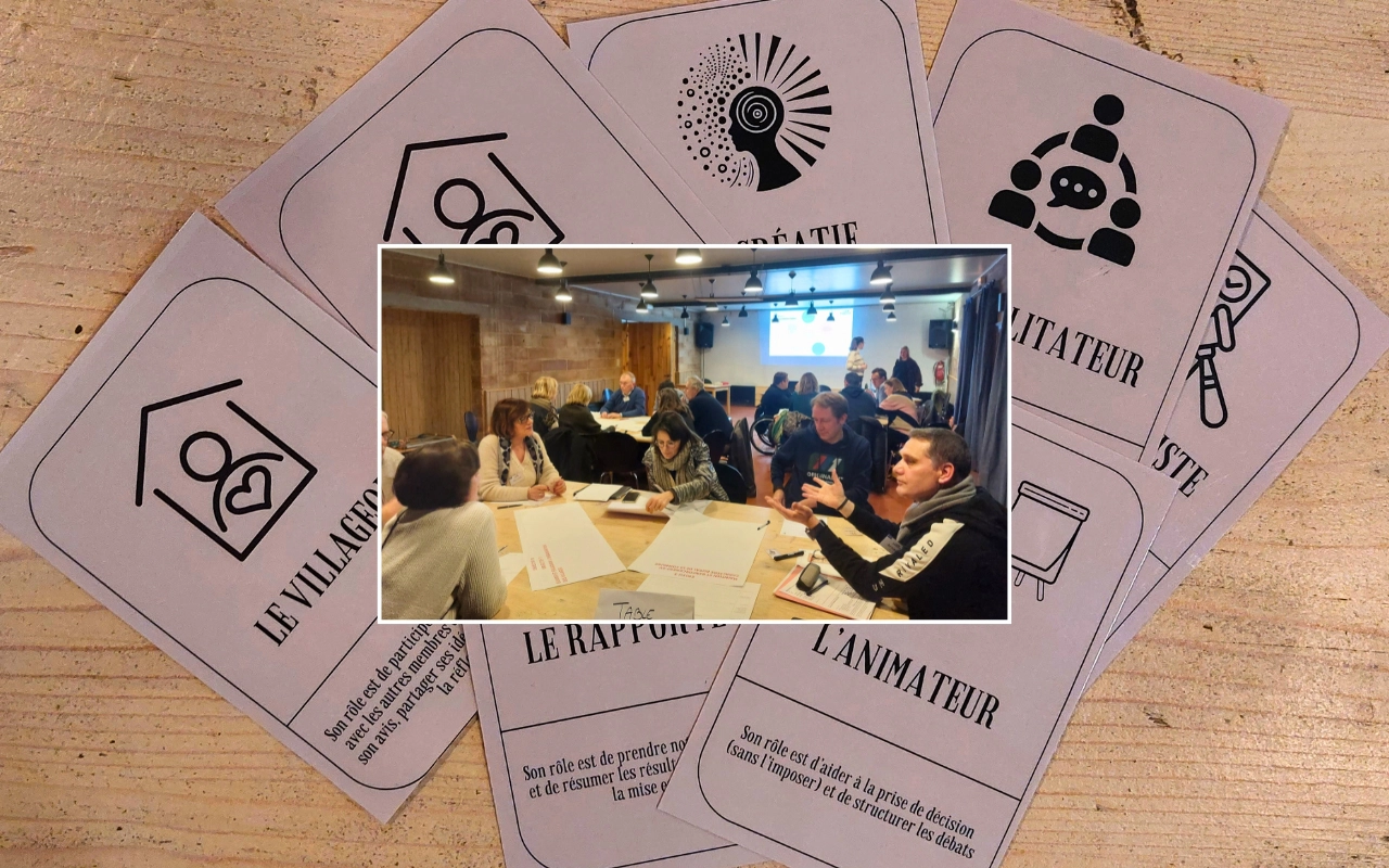 Il s'agit d'un collage. L'image principale montre les cartes des différents personnages d'une version revisitée du jeu de rôle "Loup Garou" étalées sur une table en bois. On peut voir "Le Villageois", "Le Créatif", "L'Animateur", "Le Facilitateur", "Le Rapporteur" et "Le Juriste". L'autre image montre différents groupes assis autour de tables et en pleine activité, probablement en train de prendre part à ce jeu, en petits sous-groupes, dans une vaste salle de réunions avec quelques tables et une présentation diapo en arrière-plan.