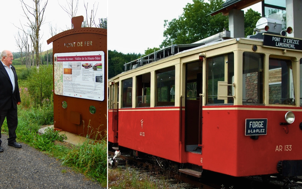 Personne debout à côté d'un panneau d'information sur le Mont de l'Her et les Mines de la Pierre-Mela. À droite, un tramway rouge et crème avec des indications de destinations telles que 'PONT D'EREZEE LAMORMENIL' et 'FORGE A LA PLEZ'